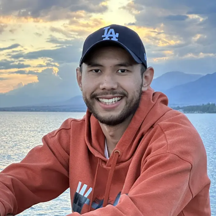 Nurbek Baizakov smiling by a lake at sunset